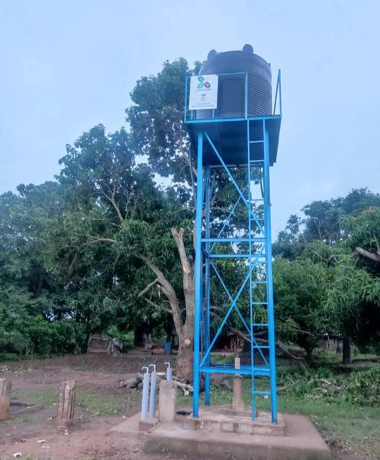 Torre metálica azul con depósito de agua entre la vegetación