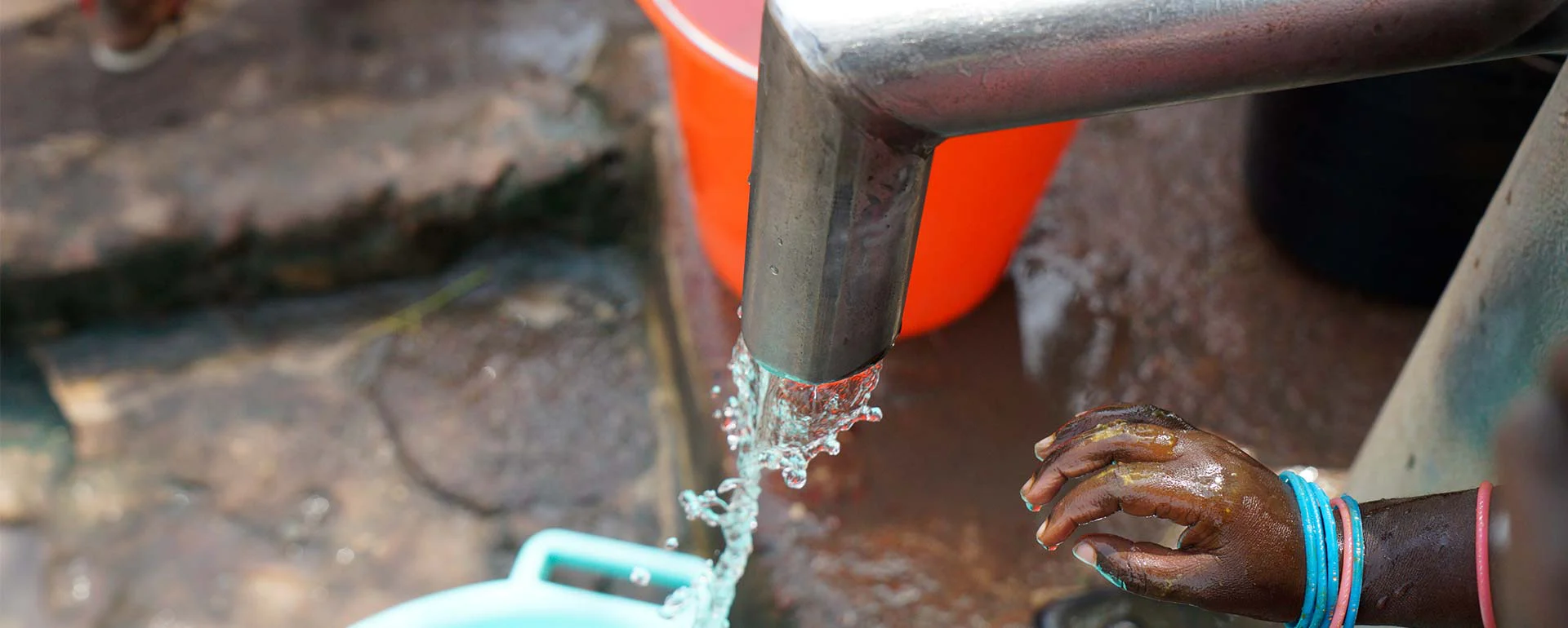 Agua saliendo de un grifo metálico en un punto de abastecimiento comunitario