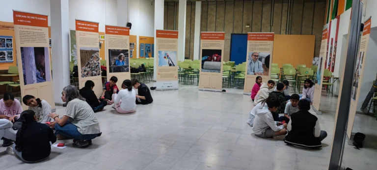 Público sentado en el suelo durante una actividad en la sala de exposiciones