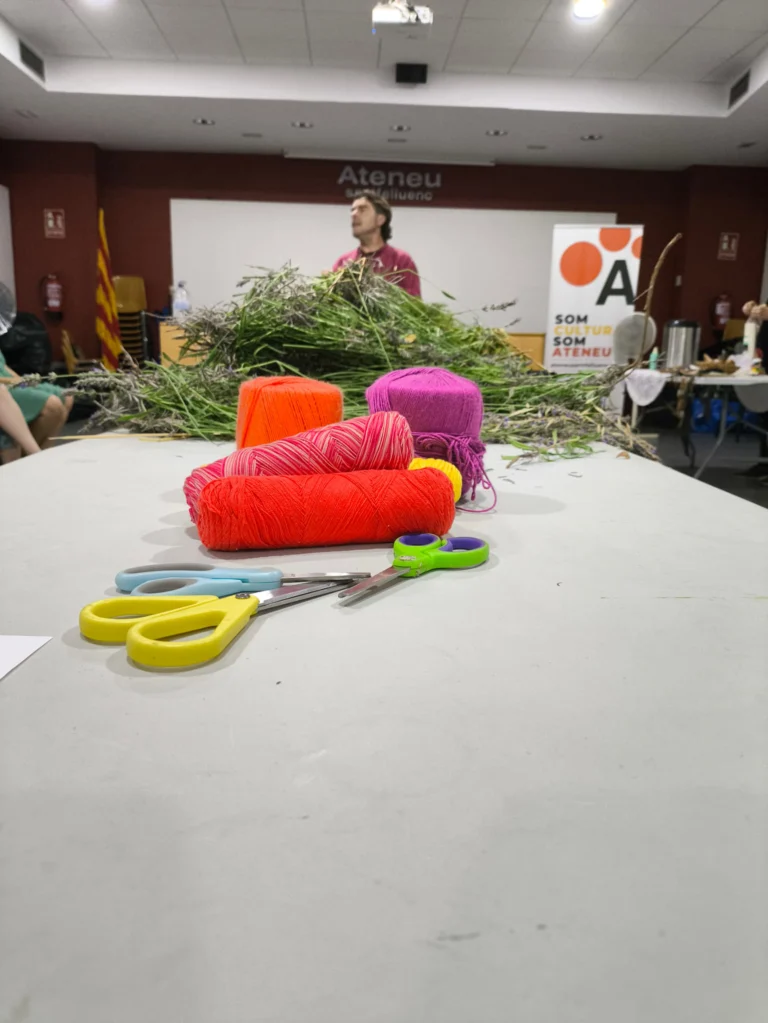 Mesa de taller con esterillas de colores, tijeras y ramas verdes