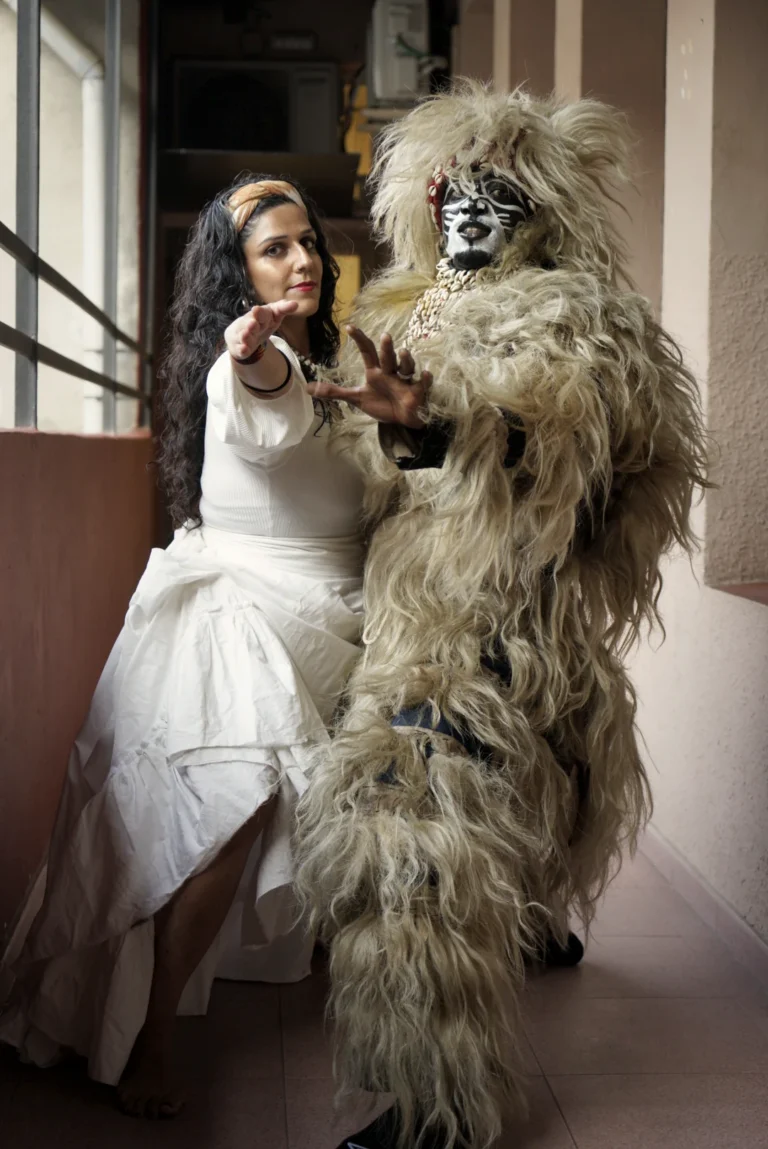 Bailarina con vestido blanco frente a un Hombre león cubierto de fibras vegetales