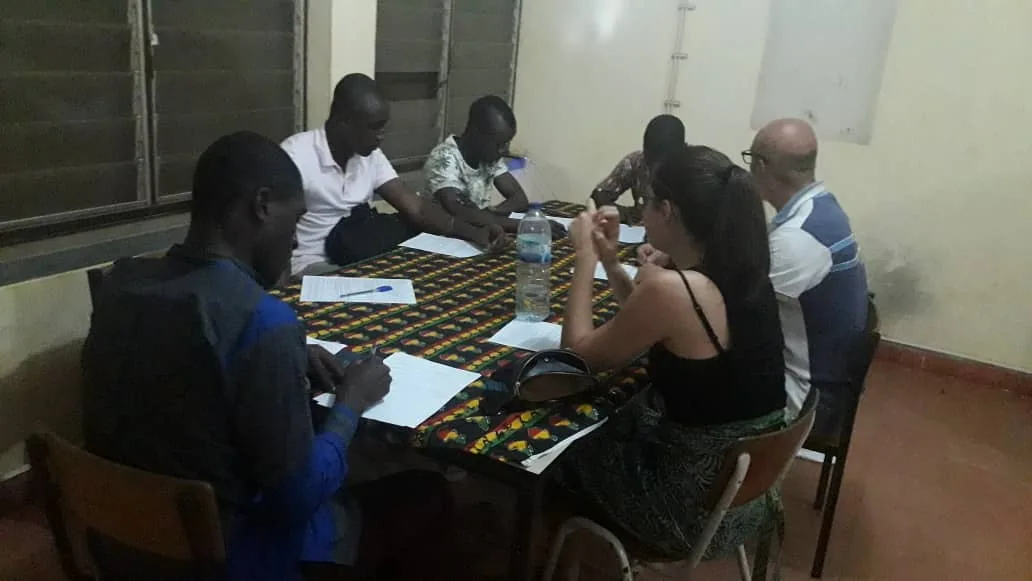 Grupo de personas reunidas alrededor de una mesa de trabajo con documentos