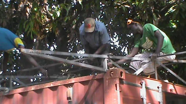 Dos hombres montando una estructura metálica junto al contenedor